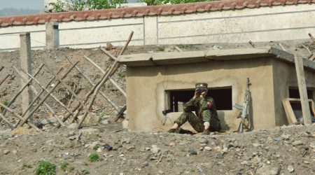 CPT6FE JI'AN, JILIN, CHINA; 20-MAY-2012. A North Korean soldier with his machine gun besides him is sitting at a guard post, watching the banks of the Yalu river facing China. © Olli Geibel